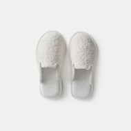 The Thuma / Lusso Cloud House Slipper is a cozy, off-white slip-on made from soft, textured fabric, shown side by side on a plain white background.