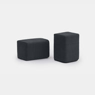 Two dark gray Pillowboard Bolsters, upholstered in fabric and rectangular in shape, are placed side by side on a plain white background. One bolster is arranged horizontally, while the other is positioned vertically.