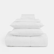 The Cotton Percale Complete Bedding Set features neatly stacked white sheets, pillowcases, pillows, and a comforter arranged in a pyramid against a plain white background.