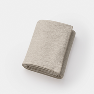 A light beige Waffle Blanket & Throw with a textured finish is neatly folded and placed on a white background.