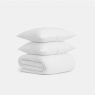 Two white pillows are stacked atop a neatly folded Cocoons Cotton Duvet Cover Set, all displayed against a plain white background.