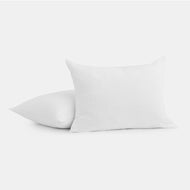 The Cocoon Cotton Sham Set, featuring two white shams with a subtle textured pattern, is displayed on a plain white background—one standing upright, the other lying flat behind it.
