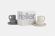 A Thuma + Heller Max Breakfast Set featuring two grey and cream mugs, plates, and saucers, displayed beside the white box with bold grey Heller text on a white background.