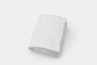 A neatly folded Cotton Gauze Blanket is displayed on a plain, light background.