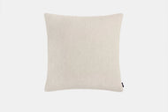 A rectangular beige Throw Pillow with a plain fabric texture is displayed against a white background, featuring a small black tag on the lower right edge.