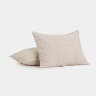 Two Linen Quilted Shams in beige with visible grid stitching, one standing upright and the other lying flat, displayed on a plain white surface.