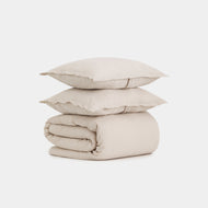 Two light beige pillows rest atop a neatly folded Linen Duvet Cover Set, all arranged against a plain white background.