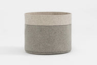 The Wool Felt Basket is a round, two-toned storage container with a light beige top, light gray bottom, visible seam stitching, and shown on a plain white background.