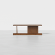 The Beam Coffee Table is a modern wooden piece with a rectangular top and base, featuring an asymmetrical central support. Shown against a plain white background.