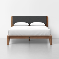 The Classic Bed - Combined Listing features a wooden frame, dark upholstered headboard, white bedding, and two pillows, set against a plain white wall and light gray floor.