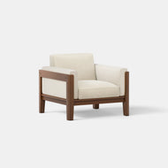 The Classic Club Chair features a modern minimalist design with a wooden frame and cream-colored cushions, set against a plain white background.
