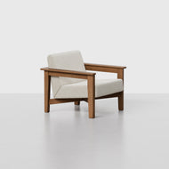 The Classic Lounge Chair features a light beige upholstered seat and backrest, complemented by wide wooden armrests and legs, set against a plain light gray background.