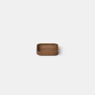 The Cove Catchall Tray, a small square brown wooden dish with rounded edges, is centered on a plain light gray background.