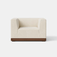 The Essential Armchair features cream-colored upholstery and a wooden base, displayed against a plain white background.