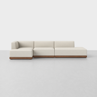 The Essential Island Chaise Sectional features cream upholstery and a wooden base, displayed on a plain white background. It comprises three modular sections, including a left-side corner seat.