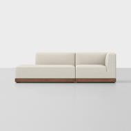 The Essential Island Sofa is a modern, minimalist sectional with cream upholstery and a wooden base, shown on a light gray floor against a plain white background.