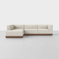 The Essential L Island Sectional is a modern L-shaped sofa with cream upholstery and a wooden base, displayed on a light gray floor against a plain white background.