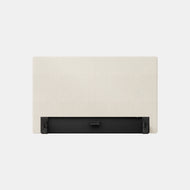 The Essential Upholstered Headboard in beige is shown from the back on a light gray background, highlighting its black metal mounting bracket.