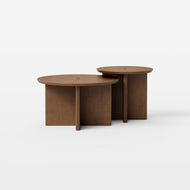 Two round, overlapping Pillar Nesting Coffee Tables with flat wooden tops and intersecting panel bases, set against a plain white background.