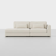 The Signature Island Sofa is a modern ivory sectional with a left-facing chaise, featuring two rectangular back cushions and two matching lumbar pillows, set against a plain light background.