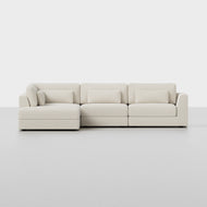 The Signature L Island Sectional is a modern light beige sofa featuring three seats, a left-side chaise lounge, three back cushions, and three matching lumbar pillows, displayed against a plain white background.