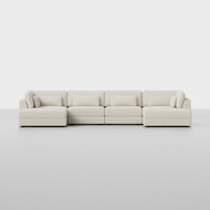 The Signature U Island Sectional, featuring a modern design with clean lines and low armrests in light beige upholstery, sits on a plain light gray floor against a white background.