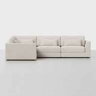 The Signature Corner Sectional is a modern L-shaped sofa in light beige, featuring clean lines and plush cushions. Its shown on a plain, light floor with a white background.