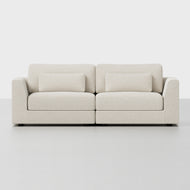 The Signature Modular Sofa features a modern beige upholstery with two seat and back cushions, plus two matching rectangular throw pillows, all set against a plain white background.