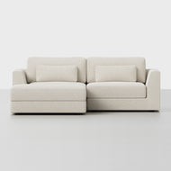 The Signature Storage Sectional is a modern light beige sofa featuring a left-side chaise, two matching lumbar pillows, and hidden storage compartments, shown against a plain white background.