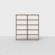 The Pillar Bookshelf is a minimalist wooden shelf with four evenly spaced tiers and a double vertical divider, displayed against a plain white background on a light gray floor.