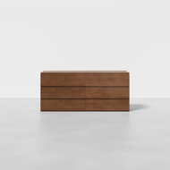 The Nest Dresser is a modern wooden dresser featuring six drawers in two columns and three rows, set on a light gray floor against a plain white background.