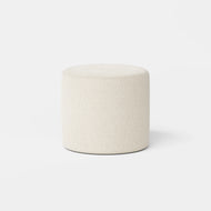 The Upholstered Ottoman features a round, beige fabric design with a smooth, cushioned top, displayed on a plain white background.